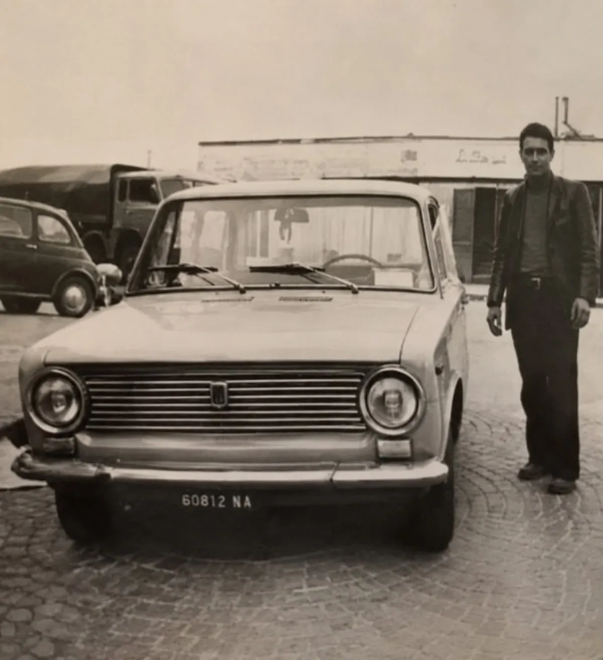 Il nonno di Massimo e Andrea accanto a un'automobile, nella fotografia di famiglia dai toni caldi