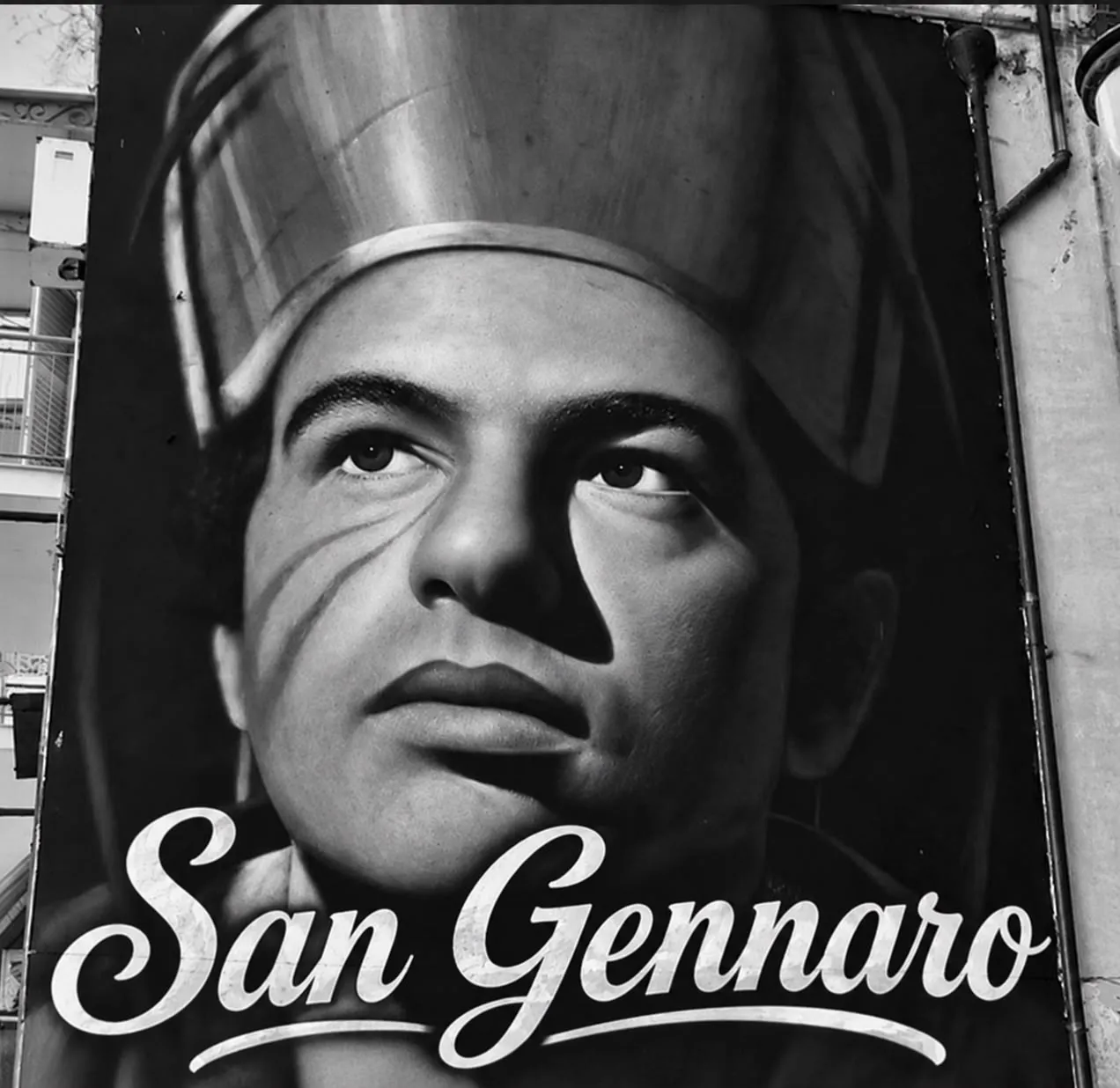 Immagine in bianco e nero su una facciata con il volto e la scritta San Gennaro