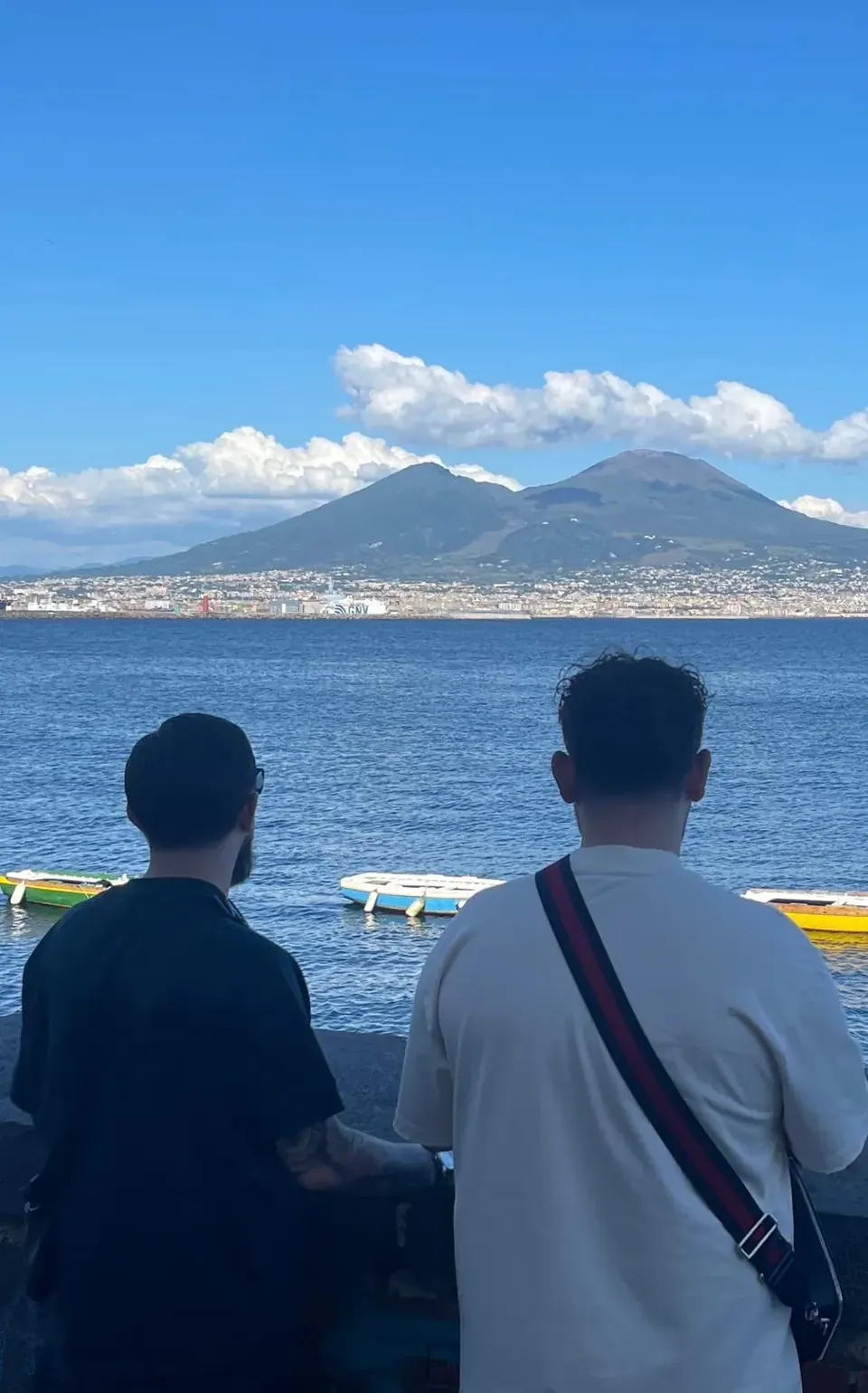 Massimo e Andrea di spalle, davanti al mare e al Vesuvio a Napoli